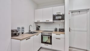 A compact kitchen with white cabinets, a built-in oven, a microwave, and a coffee maker.