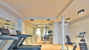 Een sportschool met loopbanden, een krachttrainingapparaat en fitnessapparatuur.