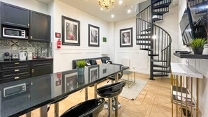 A modern kitchen with a black countertop, stainless steel appliances, and a spiral staircase.