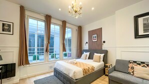 A modern bedroom with a large bed, a grey sofa, and a chandelier.