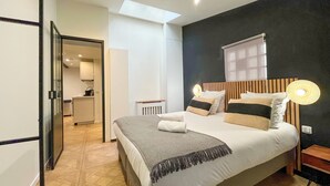 A modern bedroom with a bed, bedside table, and a window.