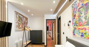 A hotel room with a large painting on the wall, a television, and a wardrobe.