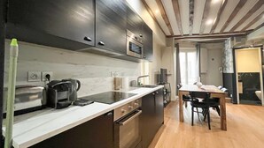 Een moderne keuken met donkere kastjes, een marmeren aanrechtblad en een houten eettafel.