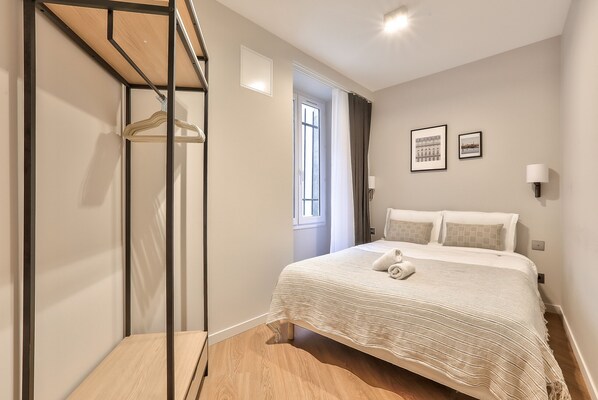 Une chambre à coucher avec un lit, une armoire suspendue, une fenêtre et une porte.