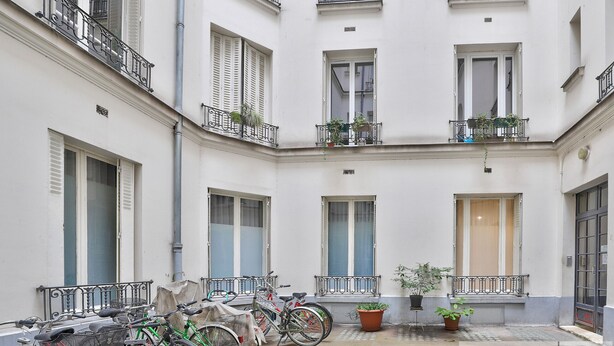 A courtyard with a central door, potted plants, and bicycles. - Urban Flat  140 - Beautiful Flat near Saint-Germain des Pres (París)
