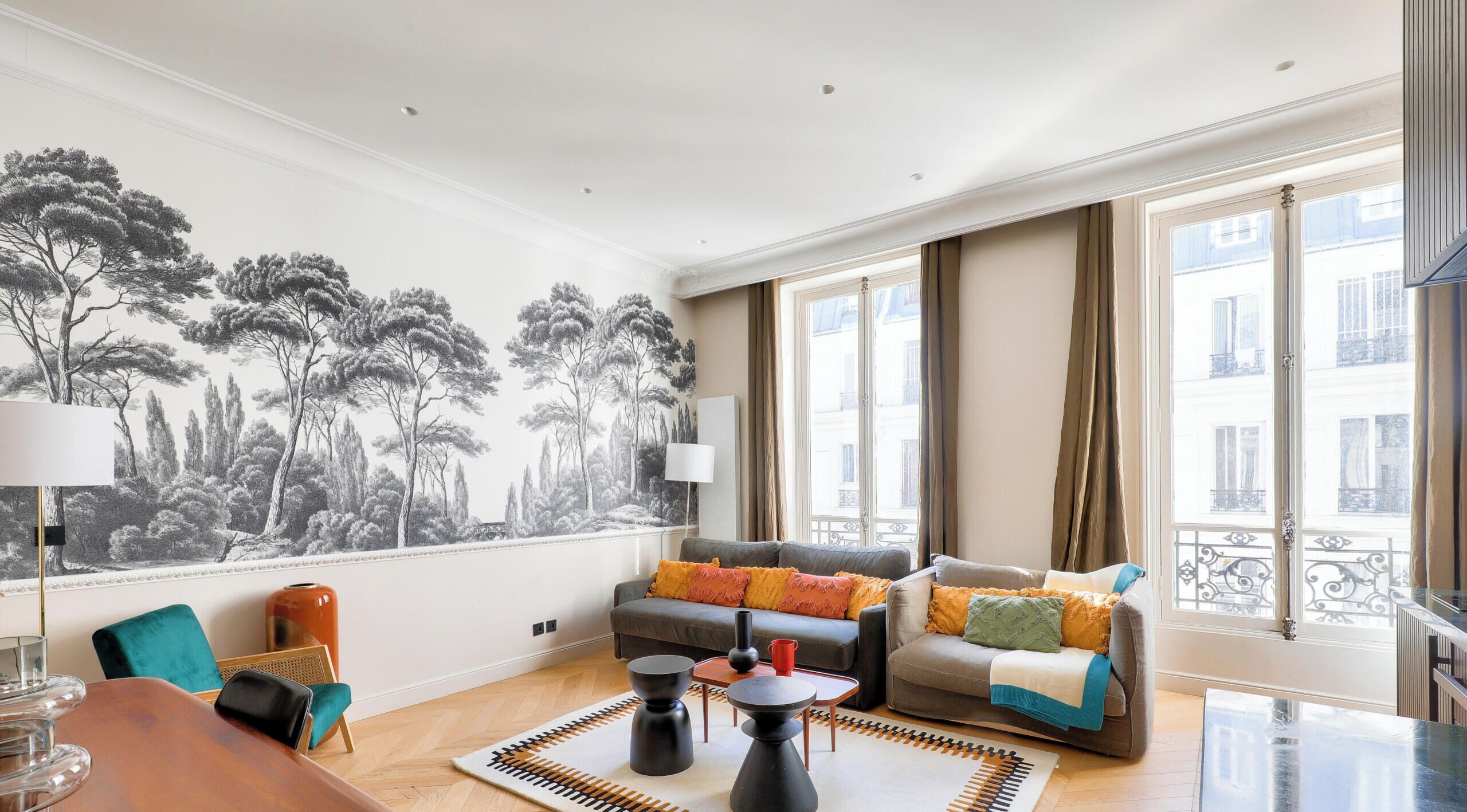 A living room with a large window, a sofa, a coffee table, and a patterned rug.