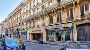 Straßenansicht mit einem Gebäude, das einen Laden für 'Eat Meat' und 'Galeries Champs' zeigt.
