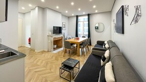 A modern living room with a sofa, a dining table, and a TV.