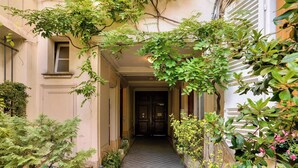 A narrow hallway with a door at the end, surrounded by greenery and plants. - Urban Flat 127 -  4 Bedroom Apartment Paris Montorgueil (París)