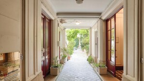 A corridor with a checkered floor, potted plants, and doors leading to rooms. - Urban Flat 127 -  4 Bedroom Apartment Paris Montorgueil (París)