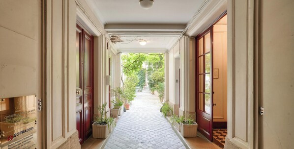 A corridor with a checkered floor, potted plants, and doors leading to rooms. - Urban Flat 127 -  4 Bedroom Apartment Paris Montorgueil (París)