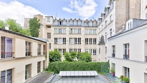 A courtyard with buildings, a metal roof, and a hedge. - UrbanFlat 92 - Prestige Apartment Paris Center (París)