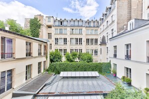 A courtyard with buildings, a metal roof, and a hedge.