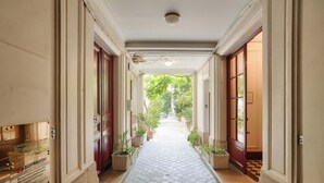 A corridor with potted plants, a tiled floor, and doors on both sides. - UrbanFlat 92 - Prestige Apartment Paris Center (París)