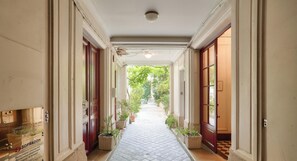 A corridor with potted plants, a tiled floor, and doors on both sides.