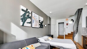Une chambre d’hôtel moderne avec un canapé gris, un lit et un escalier.