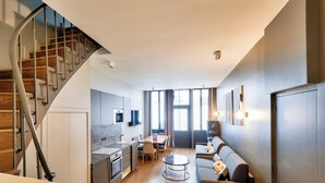 Una cocina moderna con comedor, una escalera y una sala de estar con sofá y mesa de centro.