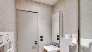 Une salle de bain moderne avec une porte blanche, un lavabo avec un miroir et un porte-serviettes.