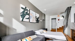 Relax in a stylish living space with a sofa, bed, and staircase leading to an upper level.