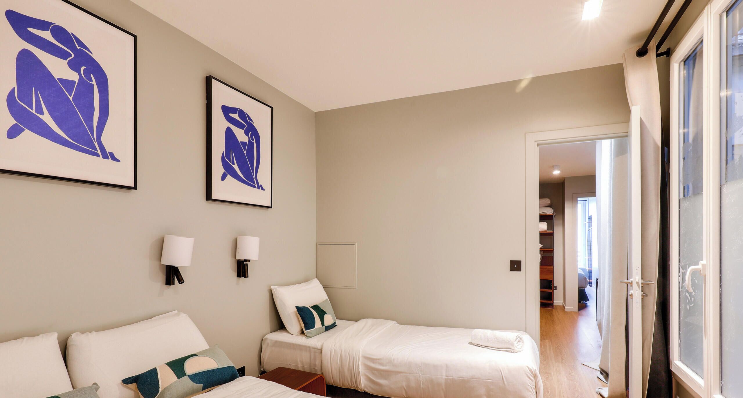 A bedroom with two beds, a wardrobe, and a bathroom visible through an open door.