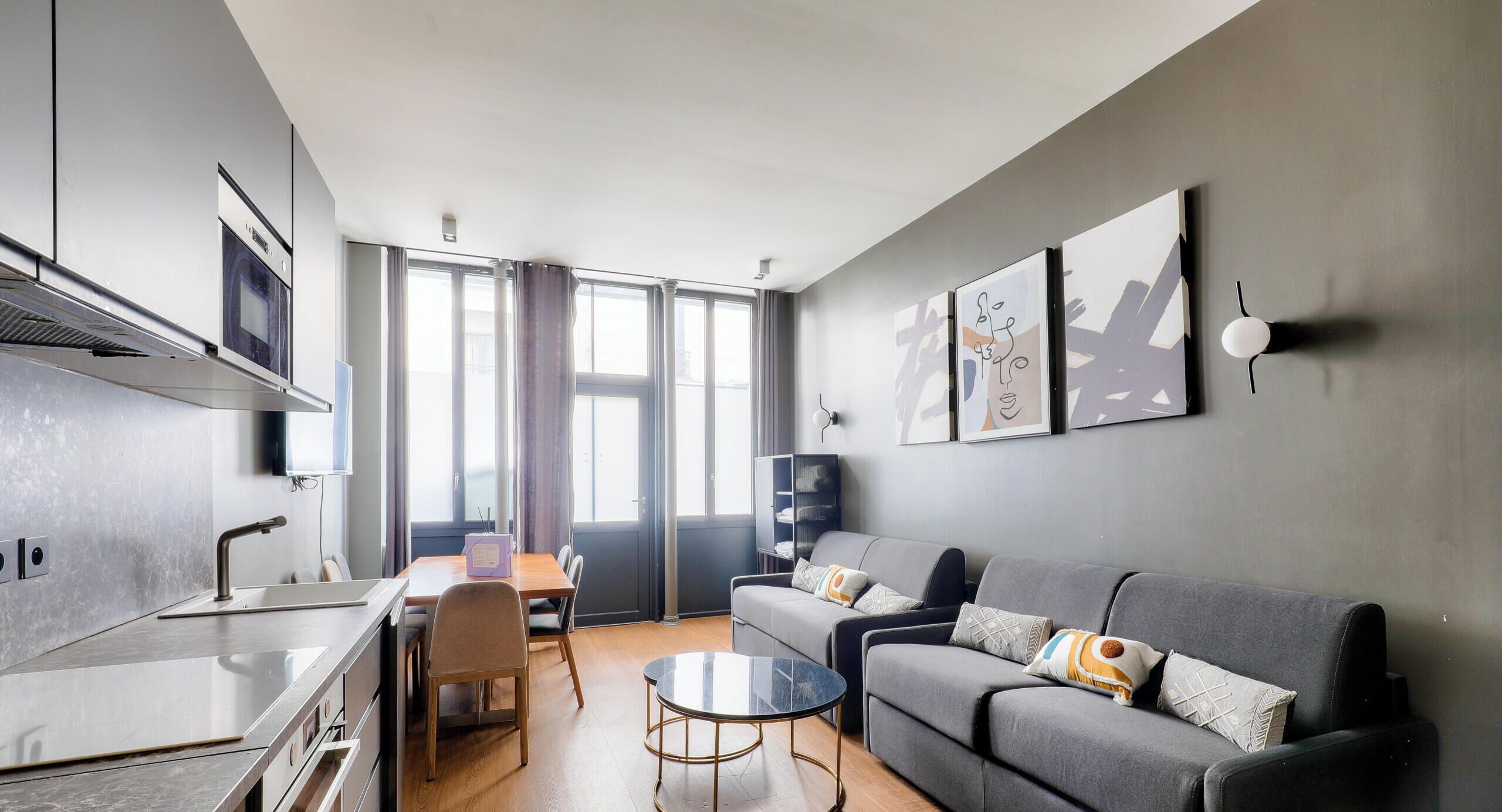 A modern living room with a grey sofa, a coffee table, and a TV mounted on the wall.