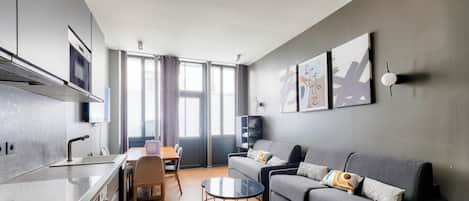 A modern living room with a grey sofa, a coffee table, and a TV mounted on the wall.