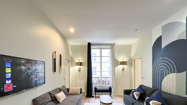 A modern living room with a flat-screen TV, two sofas, a coffee table, and a large window with a view of buildings. - 64 - Urban Luxury Flat near Champs-Elysées (París)