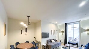 Una sala de estar moderna con una mesa redonda, sofás, televisor y un balcón.