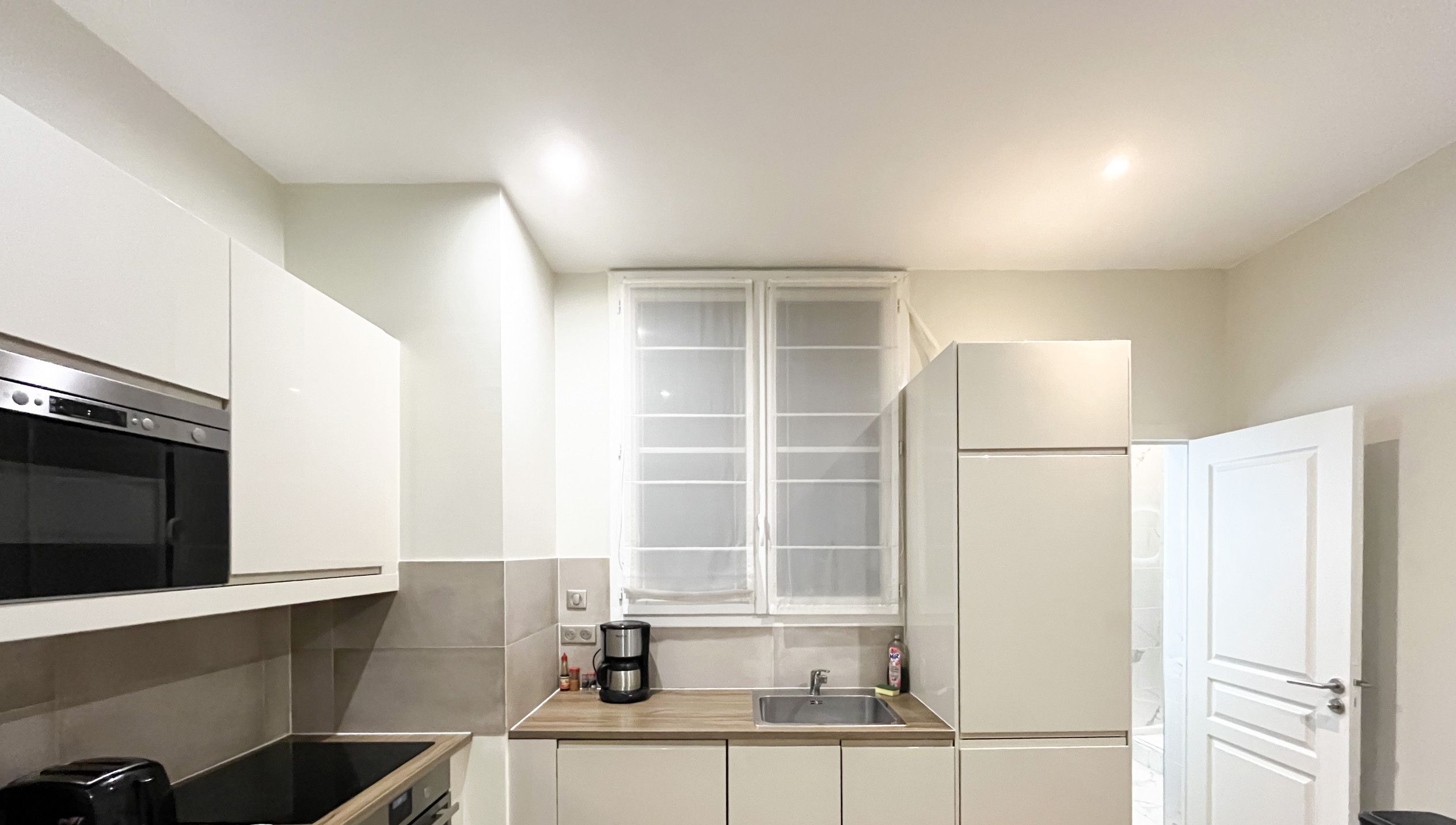 A compact kitchen with a built-in oven, a coffee maker, and a refrigerator.