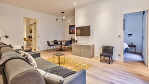 A modern living room with a sofa, a dining table, and a TV mounted on the wall. - UrbanFlat 64 - Urban Luxury Flat near Champs-Elysées (París)