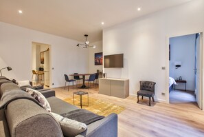 Un salon moderne avec un canapé, une table à manger et un téléviseur fixé au mur.