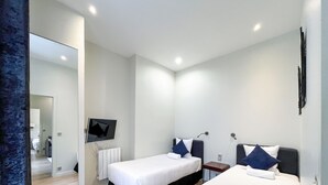A hotel room with two beds, a flat-screen TV mounted on the wall, and a bathroom visible through an open door. - UrbanFlat 64 - Urban Luxury Flat near Champs-Elysées (París)