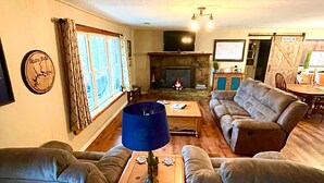 Ein Wohnzimmer mit Kamin, Sofas, einem Couchtisch und einem Fernseher.