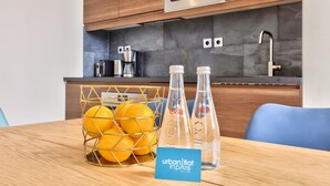 A modern kitchen with wooden cabinets, a stainless steel oven, and a marble backsplash. There is a basket of oranges and two bottles labeled "evia" on the table. - 71 - Urban Amazing Apartment in Le Marais (París)
