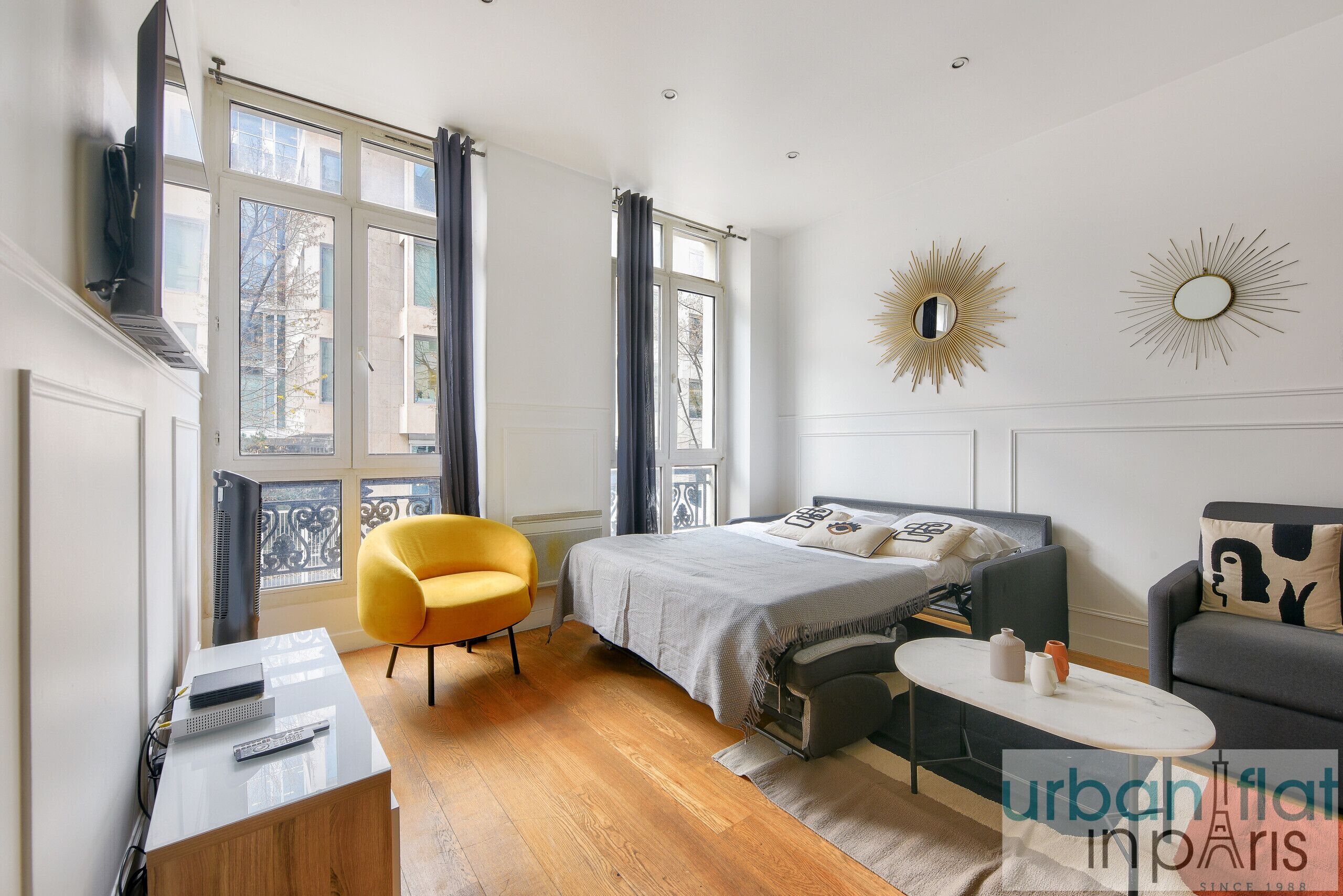A modern bedroom with a bed, a desk, a chair, and a small table.