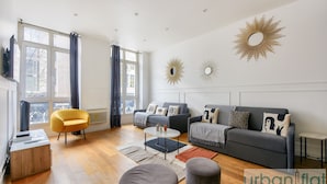 Un soggiorno moderno con divano, poltrona, poggiapiedi, tavolino e specchi decorativi.