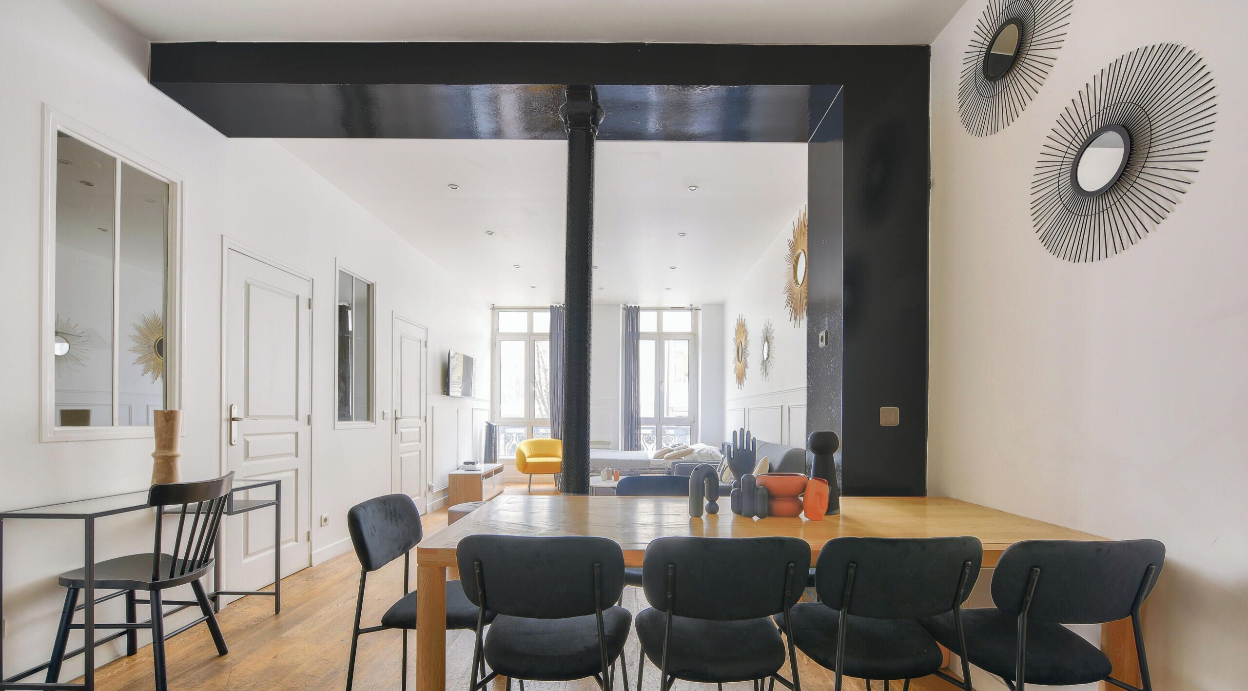 Ein moderner Wohnraum mit Essbereich, einer Küche und einem großen Fenster, das natürliches Licht hereinlässt.