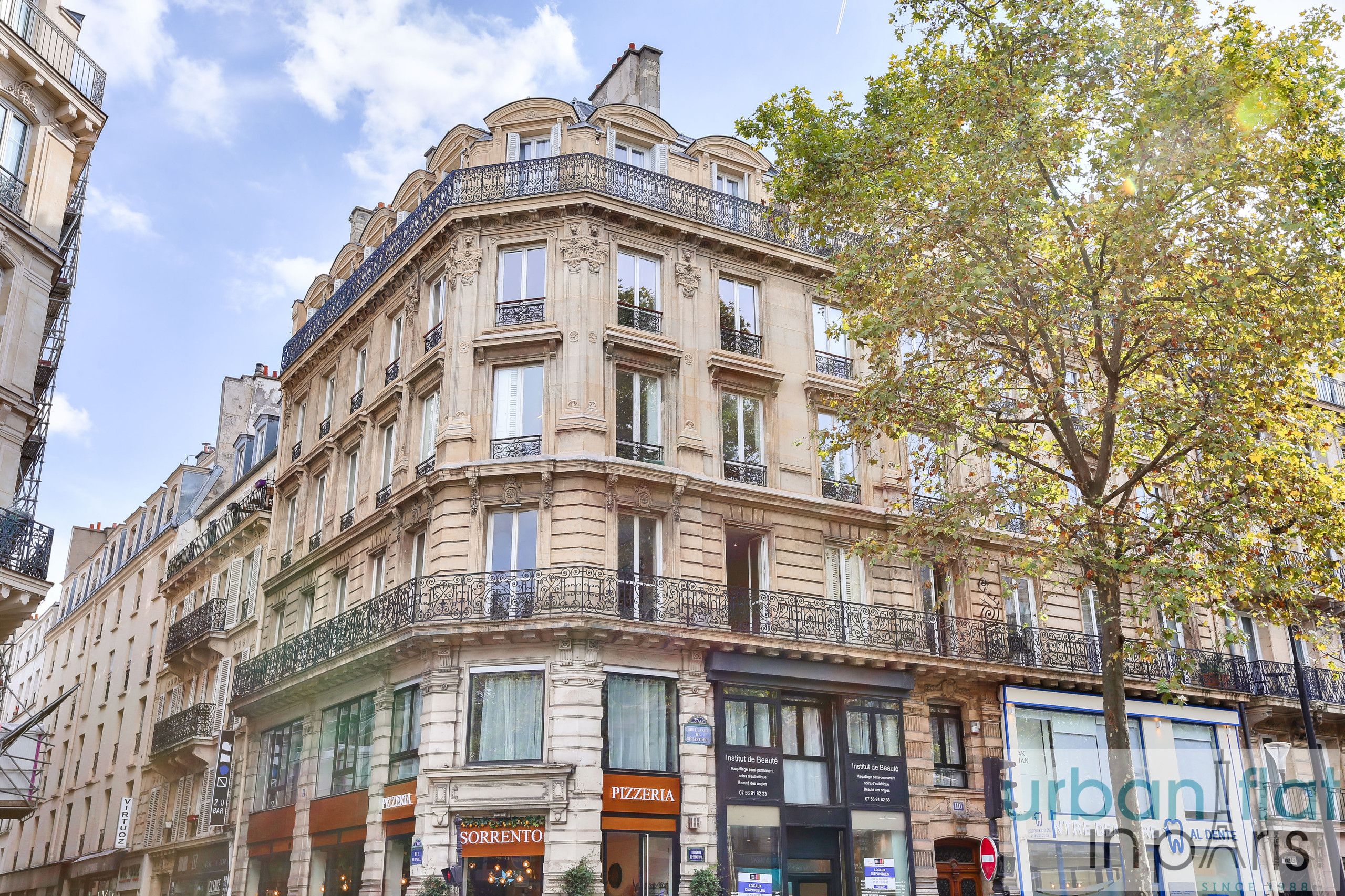 A historic building with multiple stories, ornate balconies, and commercial establishments on the ground floor.