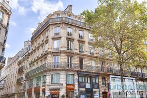 A historic building with multiple stories, ornate balconies, and commercial establishments on the ground floor.