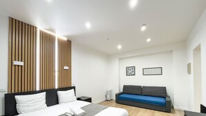 Een moderne hotelkamer met een bed, een slaapbank en een paneel dat aan de muur bevestigd is.
