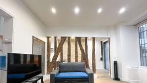 Een moderne woonkamer met een flatscreen televisie, een bank met een blauw kussen en een houten wandpaneel.
