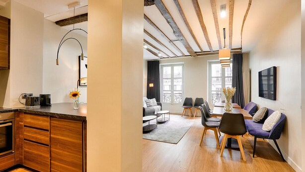 A modern kitchen with wooden cabinets and a dining area with a table and chairs.