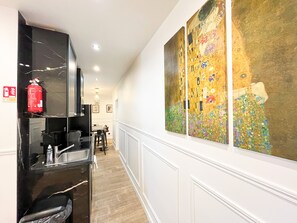 A hallway with a black marble counter, a fire extinguisher, and a large Gustav Klimt painting on the wall.