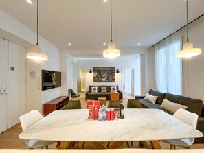 A modern dining area with a marble table, pendant lighting, and a sofa set.