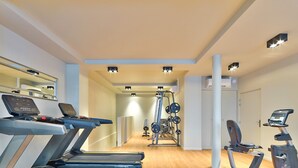 Ein modernes Fitnessstudio mit Laufbändern, Krafttrainingsgeräten und einer Spiegelwand.