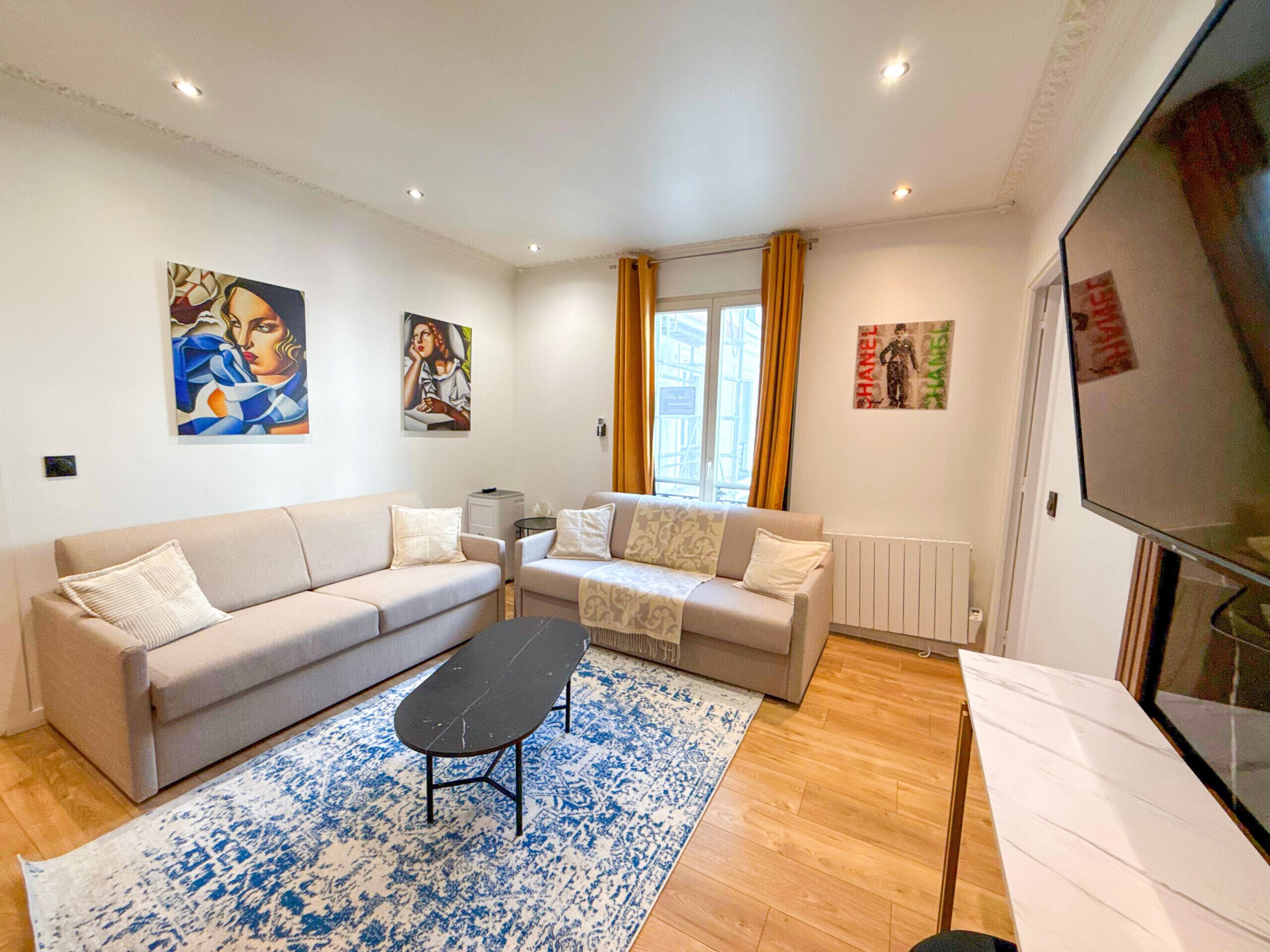 A living room with a sofa set, a coffee table, and artwork on the walls.