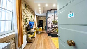 A room with a stone wall, a view of the Eiffel Tower, a dining area with yellow chairs, and a door labeled 154. - Urban Flat 154 - Pretty 2 BDR in center of Paris (París)