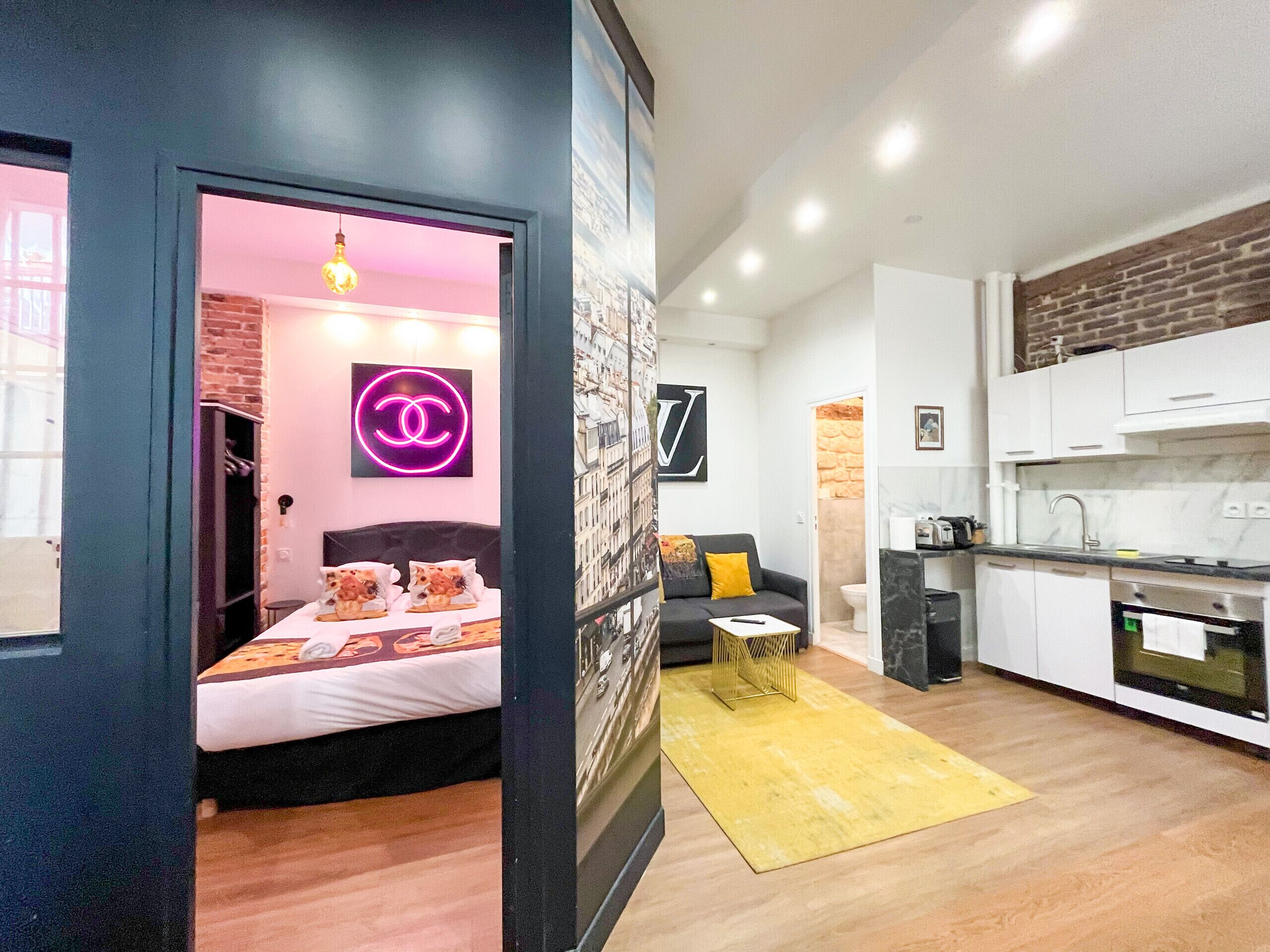 A compact living space with a bed, a sofa, a small coffee table, and a kitchen area.