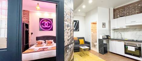 A compact living space with a bed, a sofa, a small coffee table, and a kitchen area.