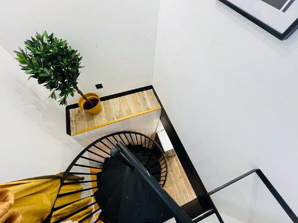 Eine Wendeltreppe mit schwarzer Handläufe, Holzboden und einer gelben Wand.